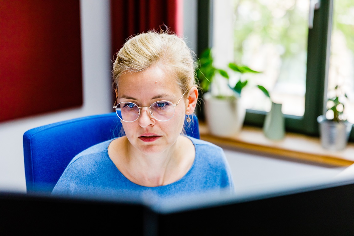 Eine Frau sitzt vor einem Computer und schaue auf den Bildschirm